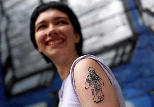 Maria Shustykova, 21, an art student, poses with her traditional Motanka (guardian angel) doll tattoo at a weekly tattoo marathon held to raise funds for the military, amid Russia's invasion, in Podil, Kyiv, Ukraine on May 21, 2022. Besides acting as her personal guardian angel, Shustykova also felt a personal connection to these dolls because she used to teach children how to make them. (Photo by Edgar Su/Reuters)