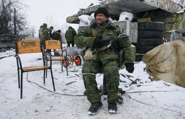 A pro-Russian separatist sits on a chair at a checkpoint in the town of Vuhlehirsk, eastern Ukraine February 10, 2015. At the front in Vuhlehirsk, a small town captured by rebels last week, volleys of artillery crashed in both directions. The rebels are pushing to encircle government forces holding out in nearby Debaltseve, a rail hub that is the main rebel target. (Photo by Maxim Shemetov/Reuters)