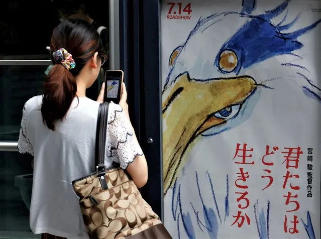 A woman takes a picture of a movie poster for Oscar-winning Japanese animation master Hayao Miyazaki's film “How Do You Live?” (Kimitachi wa Do Ikiru Ka?) outside a movie theatre in Tokyo, Japan on July 14, 2023. (Photo by Kim Kyung-Hoon/Reuters)