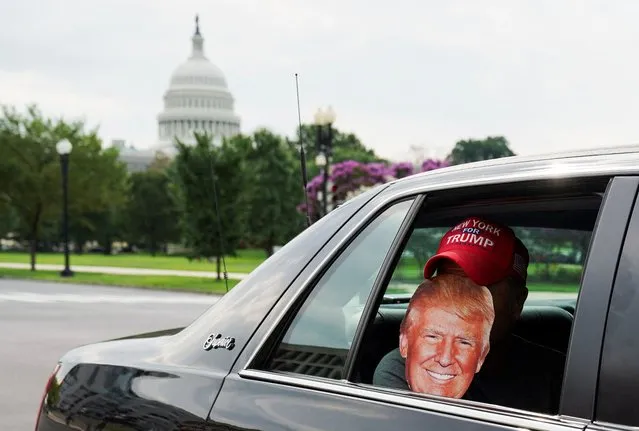 A person holds a Trump mask inside a vehicle, on the day former U.S. President Donald Trump, who is facing federal charges related to attempts to overturn his 2020 election defeat, appears at the U.S. District Court in Washington, U.S., August 3, 2023. (Photo by Sarah Silbiger/Reuters)