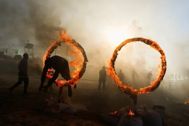 A young Palestinian jumps through a ring of fire during a military exercise at a summer camp organised by Hamas' armed wing, in Khan Younis, southern Gaza Strip on August 8, 2023. (Photo by Ibraheem Abu Mustafa/Reuters)