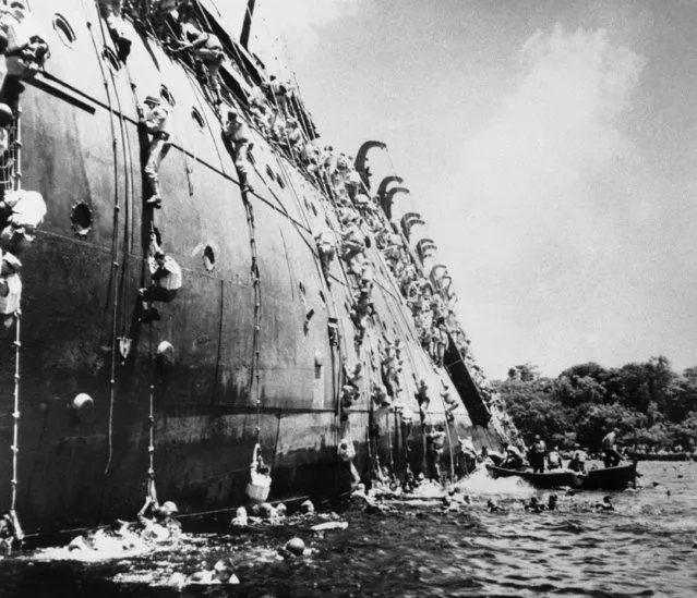 This dramatic picture, taken after the order came to abandon the SS President Collidge, the 22,000-ton troop transport, which struck a mine in a harbour on Espiritu Santo, on March 21, 1943, shows troops swarming over the side by rope and cargo net. On her captain's order the ship was run upon a reef which held it long enough for all but two men to escape. (Photo by AP Photo)