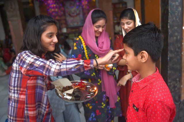 Pakistani Hindu girls with their brother celebrate the Hindu festival 'Raksha Bandhan' at a temple in Karachi on August 30, 2023. (Photo by Rizwan Tabassum/AFP Photo)