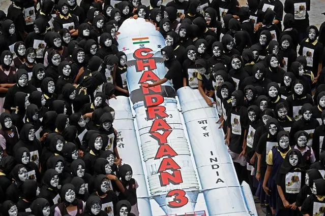 Students with painted faces surround a replica of the Chandrayaan-3 spacecraft in Chennai on August 22, 2023. The Indian Space Research Organisation (ISRO) confirmed that the lander module of the Chandrayaan-3, which means “Mooncraft” in Sanskrit, had “successfully separated” from the propulsion module six days ahead of a planned landing slated for August 23. India launched a rocket on July 14 carrying an unmanned spacecraft to land on the Moon, its second attempt to do so as its cut-price space programme seeks to reach new heights. (Photo by R.Satish Babu/AFP Photo)