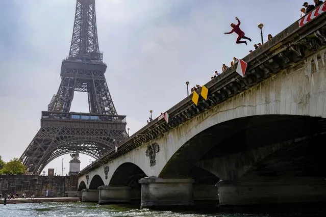 A Paris Fire Brigade (Brigade des Sapeurs Pompiers de Paris or BSPP) fireman, belonging to the La Monnaie Rescue Center, jumps from the bridge Pont d'Iena as he takes part in a training session near the Eiffel Tower on the river Seine in Paris on June 2, 2023. La Monnaie Rescue Center, situated on a barracks barge, named Commandant Beinier, also called CS La Monnaie, is the base of the river rescue unit. (Photo by Alain Jocard/AFP Photo)