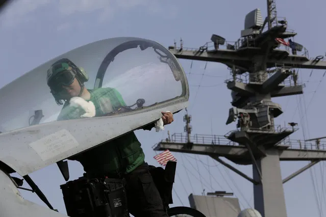 A U.S. sailor cleans the cockpit of a military jet aboard the USS Carl Vinson aircraft carrier in the Persian Gulf, Thursday, March 19, 2015. (Photo by Hasan Jamali/AP Photo)