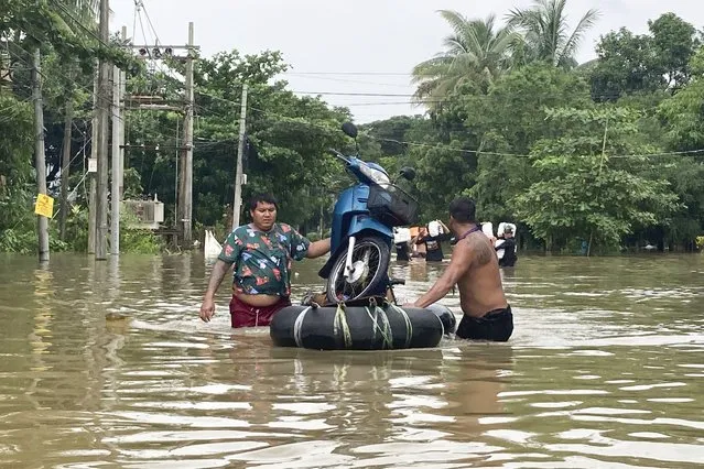 Local residents push a motorbike on a make-shift raft made of inner-tubes down a flooded road in Bago, Maynmar, about 80 kilometers (50 miles) northeast of Yangon, Friday, August 11, 2023. (Photo by AP Photo/Stringer)