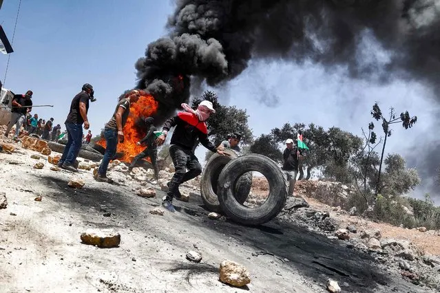 Palestinian protesters set tires aflame during clashes with Israeli security forcesf following a demonstration in the village of Beita, south of Nablus, in the occupied West Bank on June 11, 2021. (Photo by Jaafar Ashtiyeh/AFP Photo)