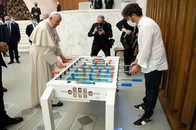Pope Francis plays with Natale Tonini, president of Sport Toscana Calcio Balilla association, at the end of the weekly general audience, Wednesday, August18. 2021. Francis played a round on the table that was presented to him  by representatives of a the association, that created a special Foosball table designed to be inclusive, for people with physical disabilities, to encourage their participation in sport. (Photo by Vatican Media via AP Photo)