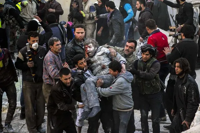 Residents carry an injured man that survived shelling after what activists said was an air strike from forces loyal to Syria's President Bashar al-Assad in Takeek Al-Bab area of Aleppo, on December 17, 2013. (Photo by Saad AboBrahim/Reuters)