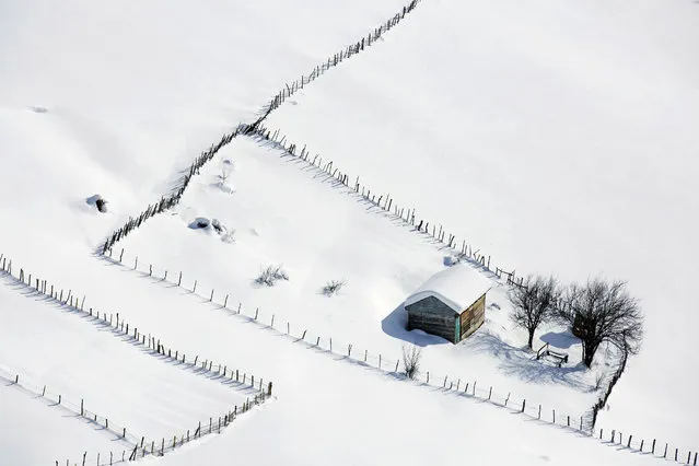 In this Tuesday, December 20, 2016 photo, a wooden cottage is covered in snow in the Talesh mountains, close to the Caspian Sea, some 262 miles (430 kilometers) northeast of Tehran, Iran. Villagers leave their wooden cottages in cold seasons due to heavy snowfall, returning in late spring to host tourists. (Photo by Ebrahim Noroozi/AP Photo)