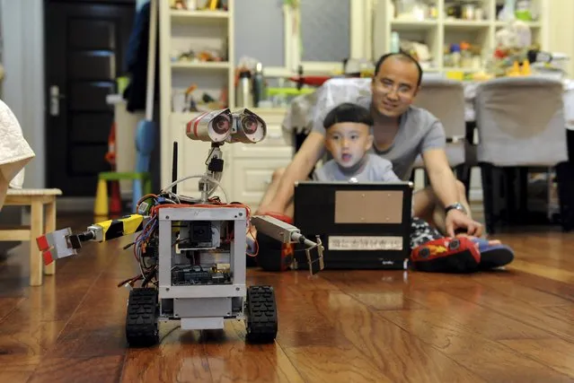 Lu Junfing (R) and his 5-year-old son test a homemade replica of robot Wall-E from the Disney-Pixar film “Wall-E”, at their home in Qingdao, Shandong province April 19, 2015. Lu spent three months and almost 10,000 yuan ($1,619) to make the remote-controlled replica, which is able to capture and transmit video and pictures, as a present for his son, local media reported. (Photo by Reuters/Stringer)