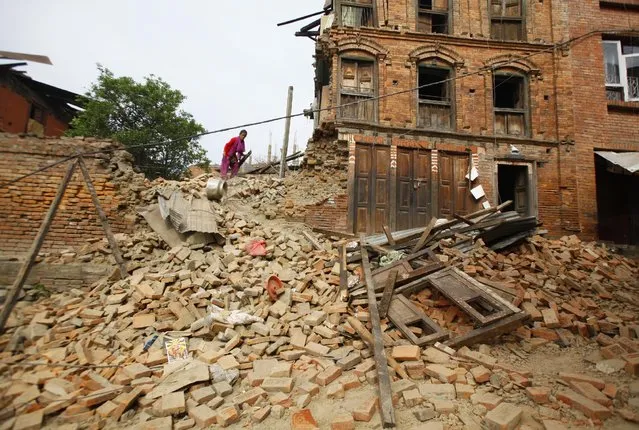 A Nepalese woman tries to find her belongings in the earthquake debris in Bhaktapur near Kathmandu, Nepal, Sunday, April 26, 2015. (Photo by Niranjan Shrestha/AP Photo)