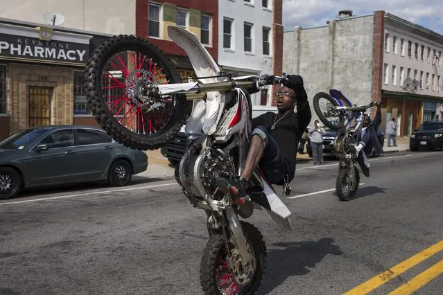 Young men pop a wheelie, or perform a stunt, along W North Avenue and Pennsylvania Avenue and near the site of a protest against the death of 25-year-old black man Freddie Gray who died in police custody in Baltimore, Maryland on April 28, 2015. (Photo by Adrees Latif/Reuters)