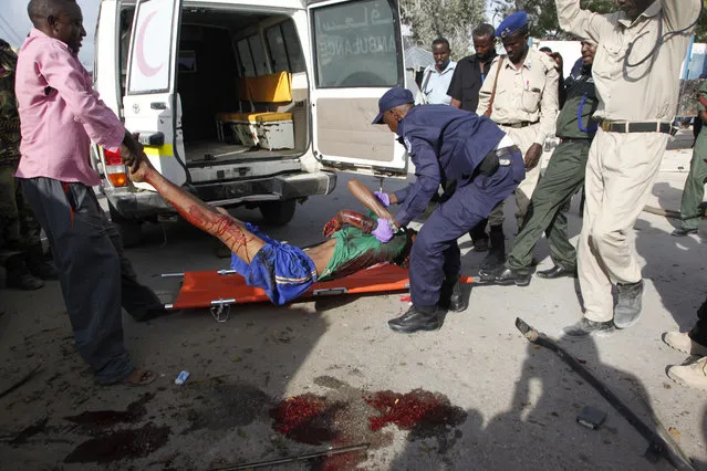Somali police officers carry a suspected suicide car bomber wounded in a bombing outside a police academy in Mogadishu, Somalia, Wednesday, March 9, 2016. A Somali police official said three police officers and one civilian have been killed in the car bombing. Gen. Ali Hersi Barre said that the suicide car bomber detonated an explosives-laden vehicle outside a cafe near the academy. (Photo by Farah Abdi Wasameh/AP Photo)