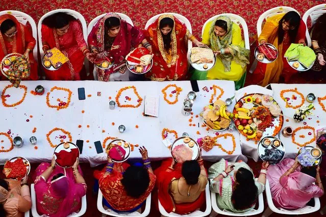 Hindu married women offer prayers during celebrations of the Karva Chauth festival, in which married women fast the whole day and offer prayers to the moon for the welfare, prosperity, and longevity of their husbands in Allahabad on October 24, 2021. (Photo by Sanjay Kanojia/AFP Photo)
