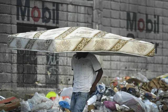 A man walks with a mattress balanced on his head in Port-au-Prince, Haiti, Wednesday, October 27, 2021. (Photo by Matias Delacroix/AP Photo)