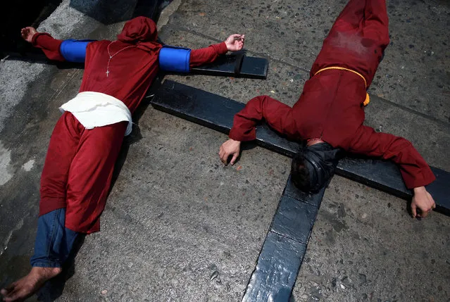 Filipino penitents bearing crosses on their backs lie on the street as they perform a ritual on Maundy Thursday in Mabalacat City, Pampanga province, Philippines, April 18, 2019. (Photo by Eloisa Lopez/Reuters)
