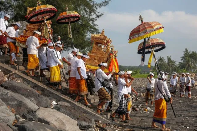 A Balinese Hindu is carrying sacred ornaments while participating in the Melasti ceremony on Masceti Beach in Gianyar, Bali, Indonesia, on March 8, 2024. The ritual, which is believed to purify and cleanse the universe, is held annually ahead of Nyepi, or the Balinese Day of Silence, which marks the new year of the Balinese Hindu calendar on March 11, 2024. Balinese will celebrate the day of seclusion on the island of Bali by not traveling, working, lighting lamps, cooking, or engaging in any other activities. (Photo by Johanes P. Christo/NurPhoto/Rex Features/Shutterstock)