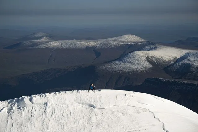 A photo taken from a helicopter shows Researcher Ninis Rosqvist at the peak of the southern summit of Kebnekaise in northern Sweden, as she uses equipment to take GPS measurements on the mountain's height on August 26, 2021. In the Arctic in Sweden's far north, global warming is happening three times faster than in the rest of the world. Kebnekaise is home to Sweden's two highest peaks. The southern summit, which was the tallest, has shrunk as the glacier at its top is melting. (Photo by Jonathan Nackstrand/AFP Photo)