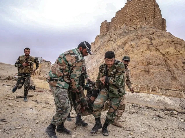 Syrian government army soldiers assist a fellow soldier who was injured in an explosion near the Fakhr al-Din al-Maani Citadel in the Unesco world heritage site in Palmyra, Syria on March 27, 2016. (Photo by Valery Sharifulin/TASS)