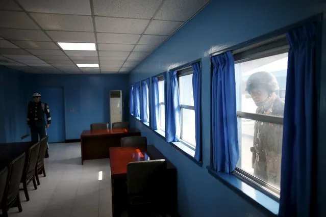 A North Korean soldier peeps into a conference room in the United Nations Command Military Armistice Commission Conference Building as a South Korean soldier stands guard, at the truce village of Panmunjom, South Korea, March 30, 2016. In the Demilitarized Zone on the heavily fortified Korean border only the Swedish and Swiss delegations to the Neutral Nations Supervisory Commission remain. The Commission was set up after the 1950-53 Korean War to uphold a fragile armistice in place of a peace treaty. (Photo by Kim Hong-Ji/Reuters)