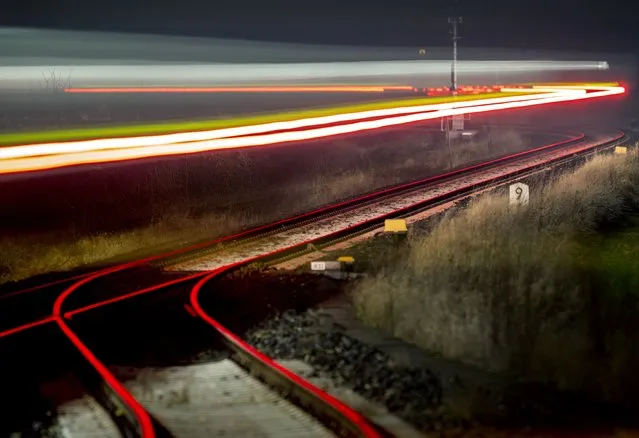 A long exposure photo shows a regional train leaving a train station in Wehrheim, Germany, Thursday, December 16, 2021. (Photo by Michael Probst/AP Photo)