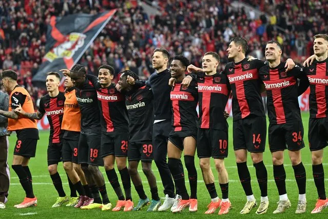 Bayer Leverkusen's Spanish head coach Xabi Alonso (C) and his players celebrate winning the German first division Bundesliga football match Bayer 04 Leverkusen v TSG 1899 Hoffenheim in Leverkusen, western Germany on March 30, 2024. (Photo by Ina Fassbender/AFP Photo)