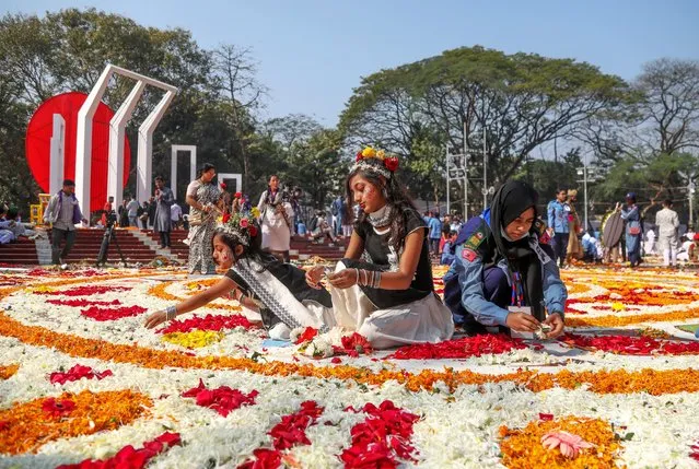 Bangladeshi volunteers and children place flowers to decorate the Central Shaheed Minar monument during Language Martyrs' Day and International Mother Language Day in Dhaka, Bangladesh, 21 February 2024. On 21 February every year, Bangladesh celebrates State Language Day or Language Martyrs' Day, which commemorates the Bengali Language Movement demonstrations in 1952. (Photo by Monirul Alam/EPA/EFE)