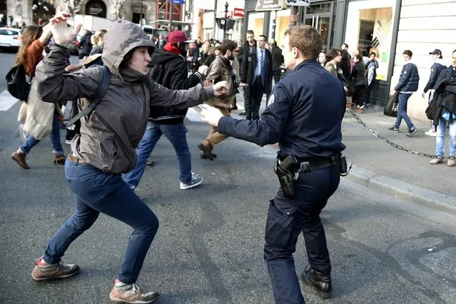 A protester clashes with a police officer during a demonstration against proposed labour law reforms, on April 12, 2016 at the Opera square in Paris. French Prime Minister Manuel Valls unveiled measures to help young people find work, aiming to quell weeks of protests against the government's proposed reforms to labour laws. Young people have been at the forefront of mass demonstrations against the reforms over the past month, which the government argues are aimed at making France's rigid labour market more flexible. (Photo by Dominique Faget/AFP Photo)