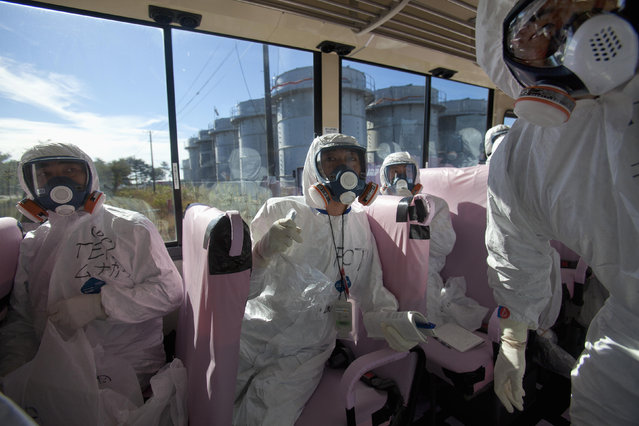 Officials from the Tokyo Electric Power Co. and Japanese journalists look at the crippled Fukushima Daiichi nuclear power plant from bus windows in Fukushima prefecture, November 12, 2011. (Photo by David Guttenfelder/Reuters)