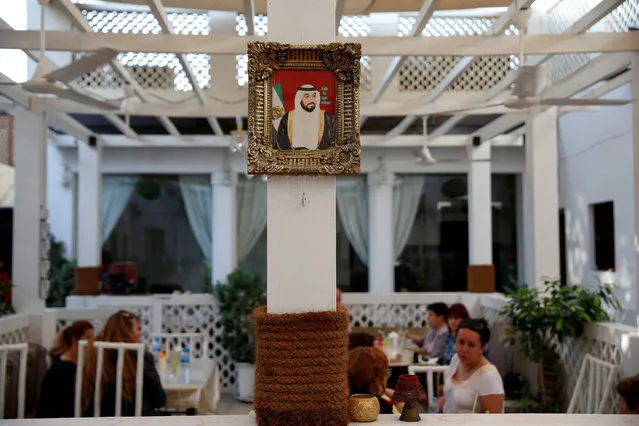 A picture of President of the United Arab Emirates Sheikh Khalifa bin Zayed bin Sultan Al Nahyan is seen as visitors sit inside a cafe in Al Bastakiya, a historic district in Dubai, UAE March 10, 2016. (Photo by Ahmed Jadallah/Reuters)