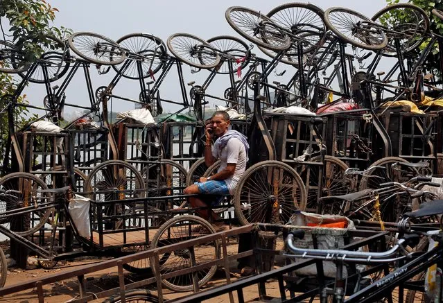 A man speaks on his mobile phone among parked trishaws in Kolkata, India, July 16, 2019. (Photo by Rupak De Chowdhuri/Reuters)