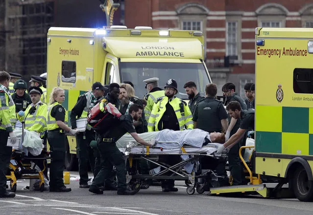 Emergency services transport an injured person to an ambulance, close to the Houses of Parliament in London, Wednesday, March 22, 2017. (Photo by Matt Dunham/AP Photo)