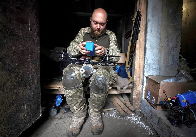 A Ukrainian serviceman of the attack drones battalion of the Achilles, 92nd brigade, attaches a shell to a first-person view (FPV) drone at his frontline position in Kharkiv Region, Ukraine, on May 15, 2024. (Photo by Inna Varenytsia/Reuters)