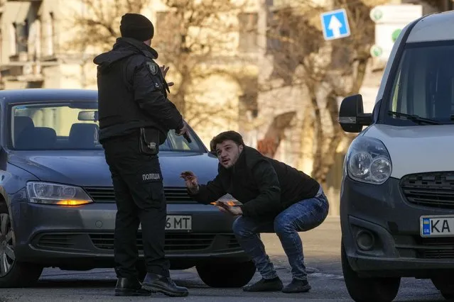 A Ukrainian police officer detains a car driver in a street in Kyiv, Ukraine, Saturday, February 26, 2022. (Photo by Efrem Lukatsky/AP Photo)