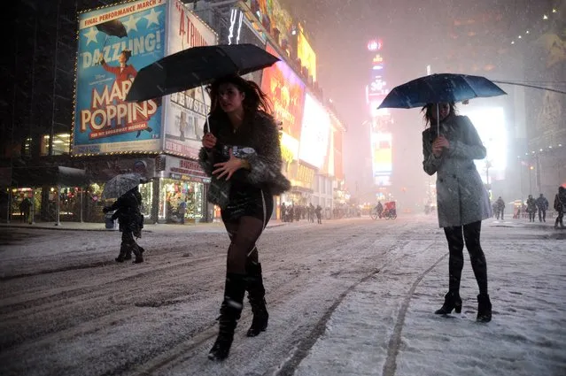 Two girls look for a taxi in the snow in Times Square in New York on February 8, 2013 during a storm affecting the northeast US. The storm was forecast to bring the heaviest snow to the densely-populated northeast corridor so far this winter, threatening power and transport links for tens of millions of people and the major cities of Boston and New York. (Photo by Mehdi Taamallah/AFP Photo)