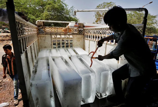 A worker of an ice factory loads an ice bar onto a truck on a hot summer day on the outskirts of Ahmedabad, India, May 13, 2016. (Photo by Amit Dave/Reuters)