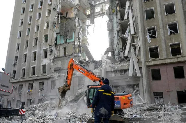 A worker watches an excavator clearing the rubble of a government building hit by Russian rockets in Mykolaiv on March 29, 2022. A Russian strike battered the regional government building in the southern Ukrainian city of Mykolaiv, a key port under heavy assault for weeks, the regional governor said on March 29, 2022. Governor Vitaly Kim said that most people inside the building had not been injured but several civilians and soldiers were unaccounted for. (Photo by Bulent Kilic/AFP Photo)