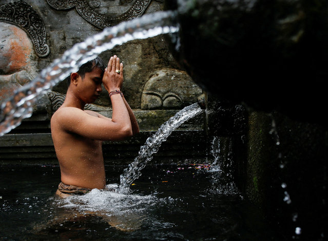 A Balinese Hindu prays before taking a bath during a cleansing ritual called Banyu Pinaruh, which is believed to purify their body and soul, at Tirta Empul temple's holy spring in Gianyar, Bali, Indonesia, on July 14, 2024. (Photo by Johannes P. Christo/Reuters)