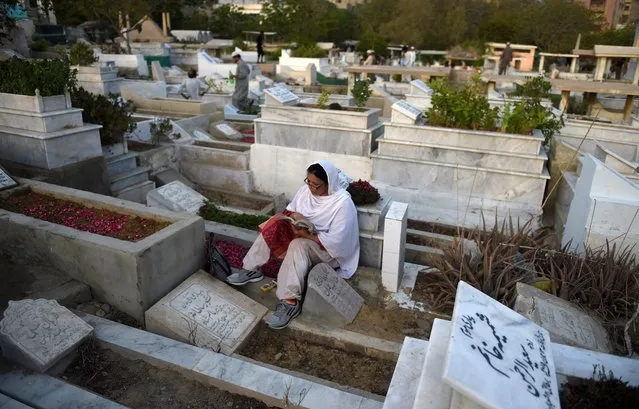 A Pakistani woman reads the Quran beside a relatives grave in a graveyard in Karachi on May 22, 2016, to mark Shab-e-Barat. Muslims across the world consider Shab-e-Barat as one of the three most sacred nights, the night of fortune and forgiveness. (Photo by Rizwan Tabassum/AFP Photo)