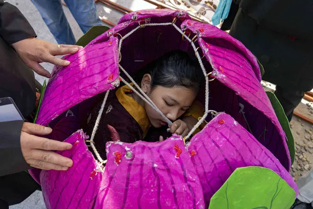 An exile Tibetan girl practices backstage inside a mechanically opening flower during a cultural dance and opera festival called “shoton” at the Tibetan Institute of Performing Arts in Dharmsala, India, Wednesday, April 6, 2022. The one-week festival has its origins in Tibet where people went on a picnic and enjoyed fresh yoghurt during the festival. (Photo by Ashwini Bhatia/AP Photo)