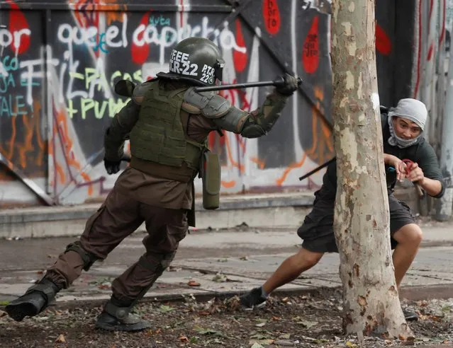 A policeman tries to hit a demonstrator during a protest against Chile's government in Santiago, Chile on December 2, 2019. (Photo by Goran Tomasevic/Reuters)