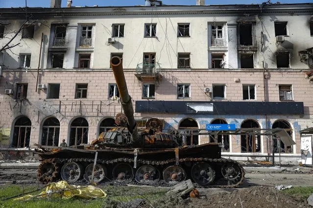 A destroyed tank and a damaged apartment building from heavy fighting are seen in an area controlled by Russian-backed separatist forces in Mariupol, Ukraine, Tuesday, April 26, 2022. (Photo by Alexei Alexandrov/AP Photo)