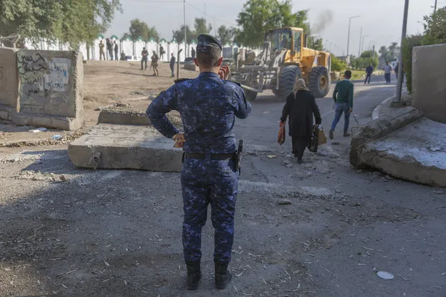 An Iraqi police officer instructs a bulldozer while Iraqi security forces remove cement blocks and opened the streets, that were closed for security concerns, around the Green Zone in Baghdad, Iraq, Thursday, January 2, 2020. Iran-backed militiamen have withdrawn from the U.S. Embassy compound in Baghdad after two days of clashes with U.S. security forces. (Photo by Nasser Nasser/AP Photo)