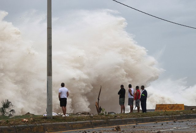 People stand in front of waves crashing against the shore as Hurricane Beryl moves south of the island, in Santo Domingo, Dominican Republic on July 2, 2024. (Photo by Erika Santelices/Reuters)