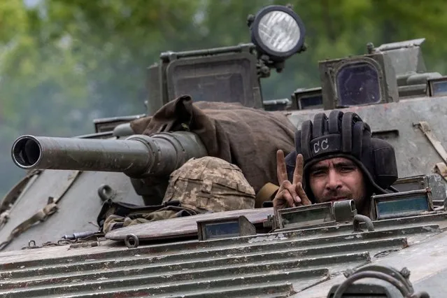 An Ukrainian service member rides on top of a military vehicle, amid Russia's invasion of Ukraine, on the road from Bakhmut to Kostyantynivka, in the Donetsk region, Ukraine on May 29, 2022. (Photo by Carlos Barria/Reuters)