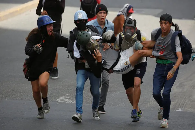 An injured demonstrator is helped by fellow protesters during clashes with riot security forces at a rally against Venezuelan President Nicolas Maduro's government in Caracas, Venezuela July 9, 2017. (Photo by Carlos Garcia Rawlins/Reuters)