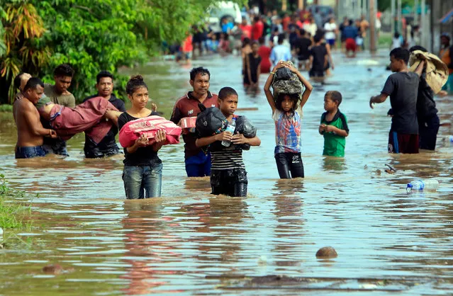 East Timorese people navigate a flooded street after heavy rains, in Tasitolu, Dili, East Timor, also known as Timor Leste, 23 J​anuary 2020. Heavy rains triggered flooding in some parts of Dili. (Photo by Antonio Dasiparu/EPA/EFE)