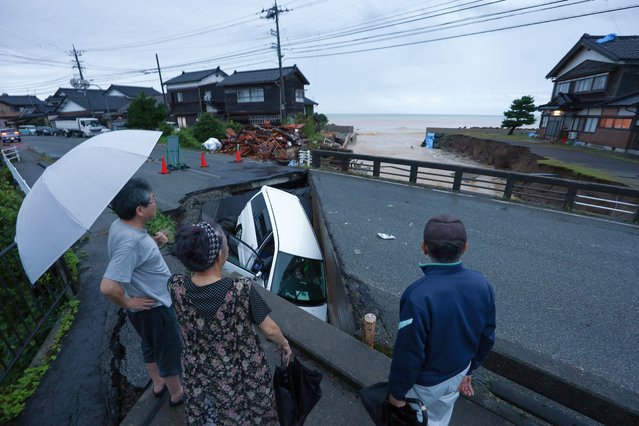 Local residents look at a car trapped in a destroyed road due to heavy rainfall in Suzu, Ishikawa Prefecture, Japan, 21 September 2024. The Japan Meteorological Agency has issued a heavy rain emergency warning for Suzu, Wajima and Noto town following torrential rain that hit New Year's Day's quake-hit Noto peninsula, causing landslides and floods. (Photo by JIJI Press/EPA/EFE)